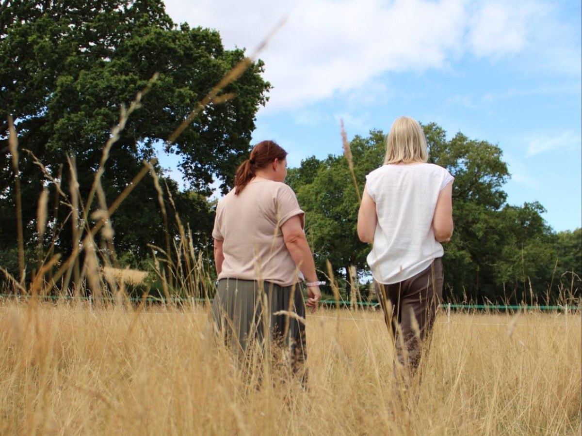 Two people walking and talking through a meadow